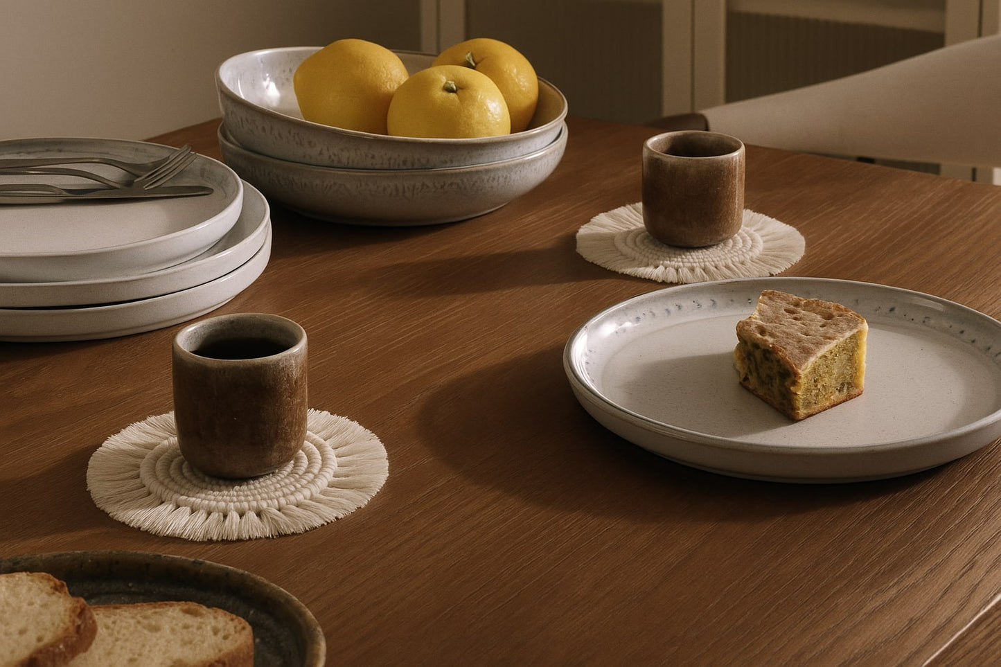 Zestaw ceramicznych naczyń na stole z podkładkami z makramy – subtelna elegancja na co dzień.